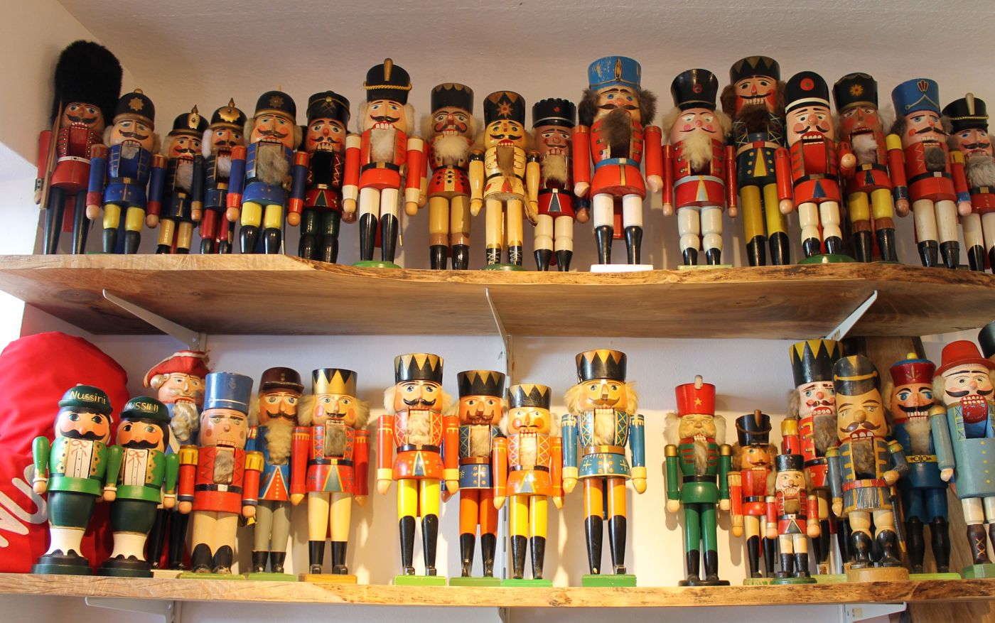 Sammlung bunter Nussknackerfiguren auf Holzregalen